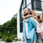 zufriedene Familie mit Kind vor Eigenheim
